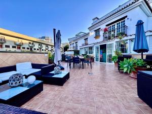 a patio with couches and tables and umbrellas at The Bajondillo terrace in Torremolinos