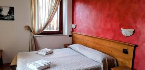 a small bedroom with a bed and a red wall at Le Bottesele in San Zeno di Montagna