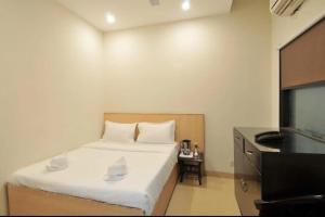 a small bedroom with a bed and a telephone at Eva Hotel in Zirakpur +2 photos