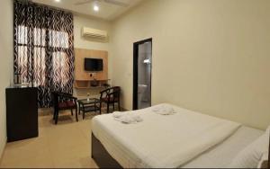 a bedroom with a bed and a table and a television at Eva Hotel in Zirakpur