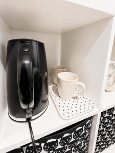 a black toaster sitting on a shelf with a coffee mug at Delwin Place - Quiet Stay & Sparkling Bathroom in Dunstable +3 photos