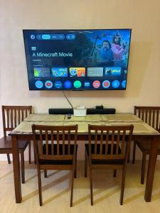 a dining room table with two chairs and a large screen at Maple Tree by The Guild Oasis Transient House in Rosario