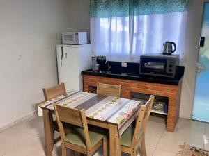a kitchen with a table and chairs and a refrigerator at Recanto das Tartarugas Flats in Penha