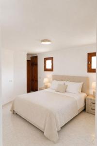 a white bedroom with a white bed and two lights at Excelente villa With pool ibiza in Santa Gertrudis de Fruitera