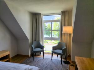 a hotel room with two chairs and a window at Bodensee-Schloss Maurach in Uhldingen-Mühlhofen +44 photos