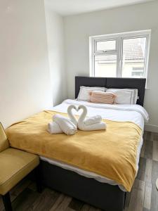 two towels shaped like hearts are sitting on a bed at Summerfields cottage stylish Home in Hollington