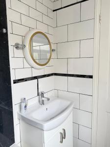 a white bathroom with a sink and a mirror at Summerfields cottage stylish Home in Hollington +7 photos