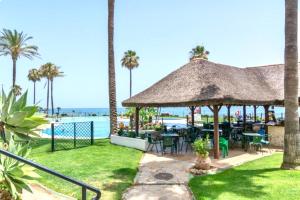 a patio with tables and chairs next to the ocean at MI CAPRICHO BEACHFRONT 410 - Apartment with terrace and private garden by the sea in Mijas Costa