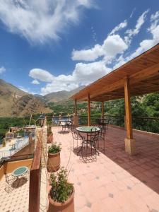 a patio with tables and chairs and mountains in the background at Azul Atlas Lodge in Imlil