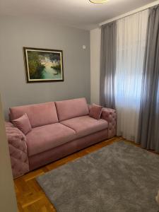 a living room with a pink couch in front of a window at Apartman BIANKA in Bijeljina