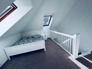 a white bedroom with a bed and a staircase at Apart Aurum B&M in Jáchymov