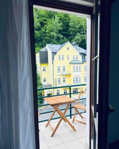 a table on a balcony with a view of a building at Apart Aurum B&M in Jáchymov