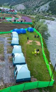 a row of blue and green tents in a field at TIS Zipline Campingsite in Gurais