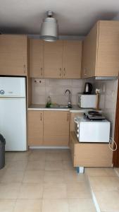a kitchen with wooden cabinets and a white refrigerator at Athos Cape Traditional House in Pyrgadikia