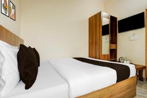 a bedroom with a white bed with a wooden headboard at Hotel O by OYO Saptagiri Comforts in Bangalore