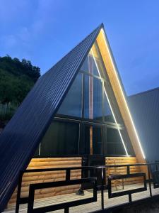 a house with a triangular roof and two benches at Bujtina Panorama Kir in Kashec