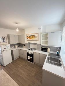 a kitchen with white cabinets and a sink at Summerfields cottage stylish Home in Hollington