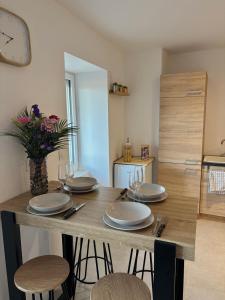 a wooden table with chairs and plates and a clock at Studio Cocon & Bulle in La Côte-Saint-André