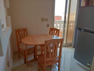 a kitchen with a wooden table and chairs and a refrigerator at Qasr Diana in Marsa Matruh