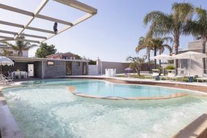 a swimming pool with blue water and palm trees at Aqua Suites Doria in Syracuse