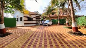 a white car parked in a parking lot with palm trees at Sahil Private Pool Villa in Alibaug