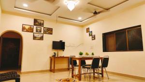 a dining room with a table and chairs and a tv at Sahil Private Pool Villa in Alibaug