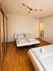 two beds in a room with wooden floors at VeloVibe apartman in Balatonalmádi