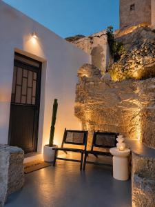 a patio with two chairs and a cactus next to a building at VR Chora Apartments in Serifos Chora