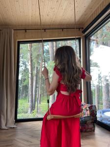 a young girl in a red dress on a swing at Connect Cabin - Bungalow Brasov, jacuzzi & forest view in Purcăreni
