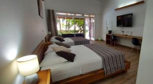 a bedroom with two beds and a desk and a television at Hotel Cahuita Inn in Cahuita