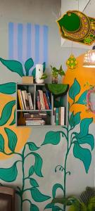 a book shelf with books and a tree painted on the wall at Garser Bantul in Yogyakarta
