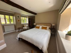a bedroom with a bed with white sheets and orange pillows at Hinton Hayloft in Hinton in the Hedges