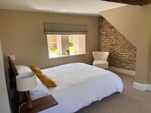 a bedroom with a white bed and a brick wall at Hinton Hayloft in Hinton in the Hedges