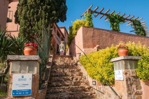 eine Treppe, die zu einem Gebäude mit Blumentöpfen führt in der Unterkunft Pierre & Vacances Villa Romana in Tossa de Mar