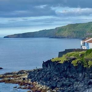 a house on a cliff next to a body of water at Estrela do Frade in Maia