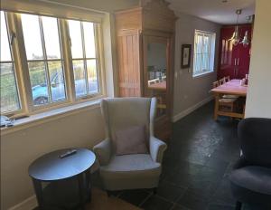 a living room with a chair and a table and windows at Harris Cuckoo Cottage in Luskentyre
