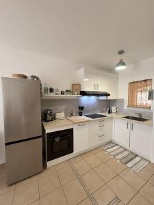 a kitchen with white cabinets and a stainless steel refrigerator at Holidays font mourrier in Cogolin +12 photos