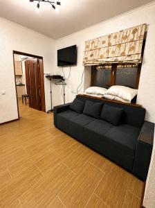a living room with a black couch and a television at Дом у Озера in Priozersk