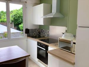 a kitchen with white cabinets and a stove top oven at Pas Sages in Le Tréport