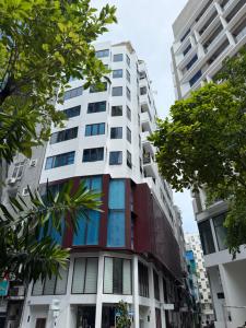 a tall white building with trees in front of it at ZAN Lodge in Male City