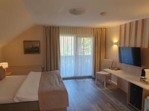 a hotel room with a bed and a desk with a television at Hotel Garni Eichhornkobel in Faßberg