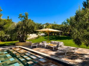 a patio with a table and chairs and an umbrella at Maisonnette Olea Hammamet in Hammamet
