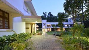 a large white building with a courtyard in front of it at Trance Sunderban Resort in Pune
