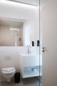 a white bathroom with a sink and a toilet at CPH Studio Hotel in Copenhagen