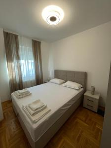 a bedroom with a white bed with towels on it at Apartman BIANKA in Bijeljina