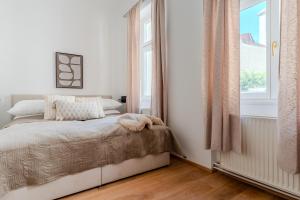 a white bedroom with a bed and a window at Hakuna Marktquartier 9 - Terrassenwohnung Spitz in Spitz