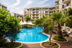 a pool at a resort with palm trees and buildings at Harmony Suites apartment 4 floor in Sunny Beach