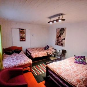 a room with three beds and a table in it at Hospedaje Luna in Valdivia