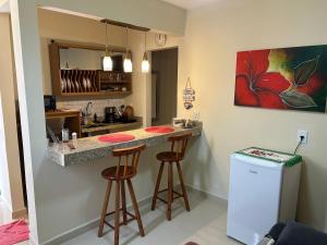 a kitchen with a counter and two stools at a bar at Chalé 3 vista para montanha in Itatiaia