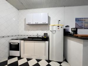 a kitchen with white appliances and a checkered floor at Flat Jubarte Praia do Francês in Marechal Deodoro +3 photos
